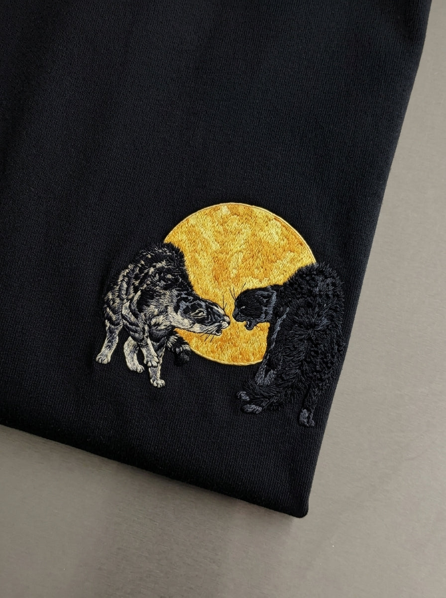TWO CATS FIGHTING AGAINST THE SILHOUETTE OF THE MOON